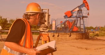 Ingeniero en petróleo realizando levantamiento topográfico en campo con maquinaria extractiva de fondo, aplicando conocimientos en energías y exploración.