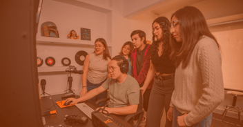 Estudiantes en sala de producción audiovisual colaborando en proyecto creativo, enfocados en dirección de empresas de entretenimiento y gestión de talentos.