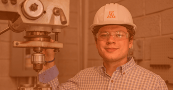 Estudiante de ingeniería civil en laboratorio con casco y gafas de seguridad operando maquinaria, en entorno universitario de formación técnica.