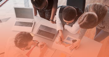 Estudiantes universitarios trabajando en equipo con laptops y gráficos financieros, desarrollando soft skills como liderazgo, comunicación y trabajo colaborativo en la Universidad Anáhuac.