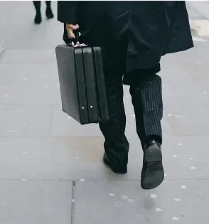 Hombre caminando con maletín en una mano.