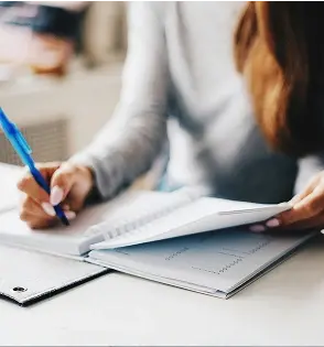 Mujer escribiendo con pluma en una libreta.