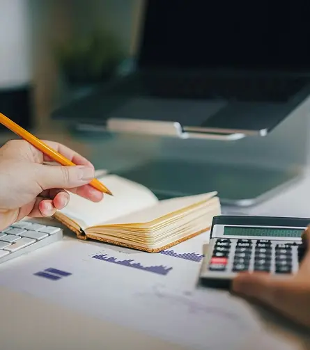 Persona escribiendo y usando una calculadora.